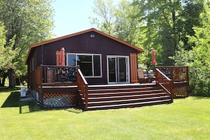 A cabin with a deck, a covered patio, and a large window.