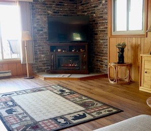 A living room with a fireplace, a television, and a wooden floor.