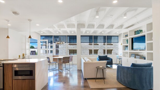 A modern open-plan living area with a kitchen, dining space, and seating area. - Luxury Downtown Retreat | Heated Pool Access (Savannah)