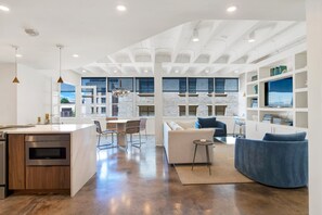 A modern open-plan living area with a kitchen, dining space, and seating area. - Luxury Downtown Retreat | Heated Pool Access (Savannah)