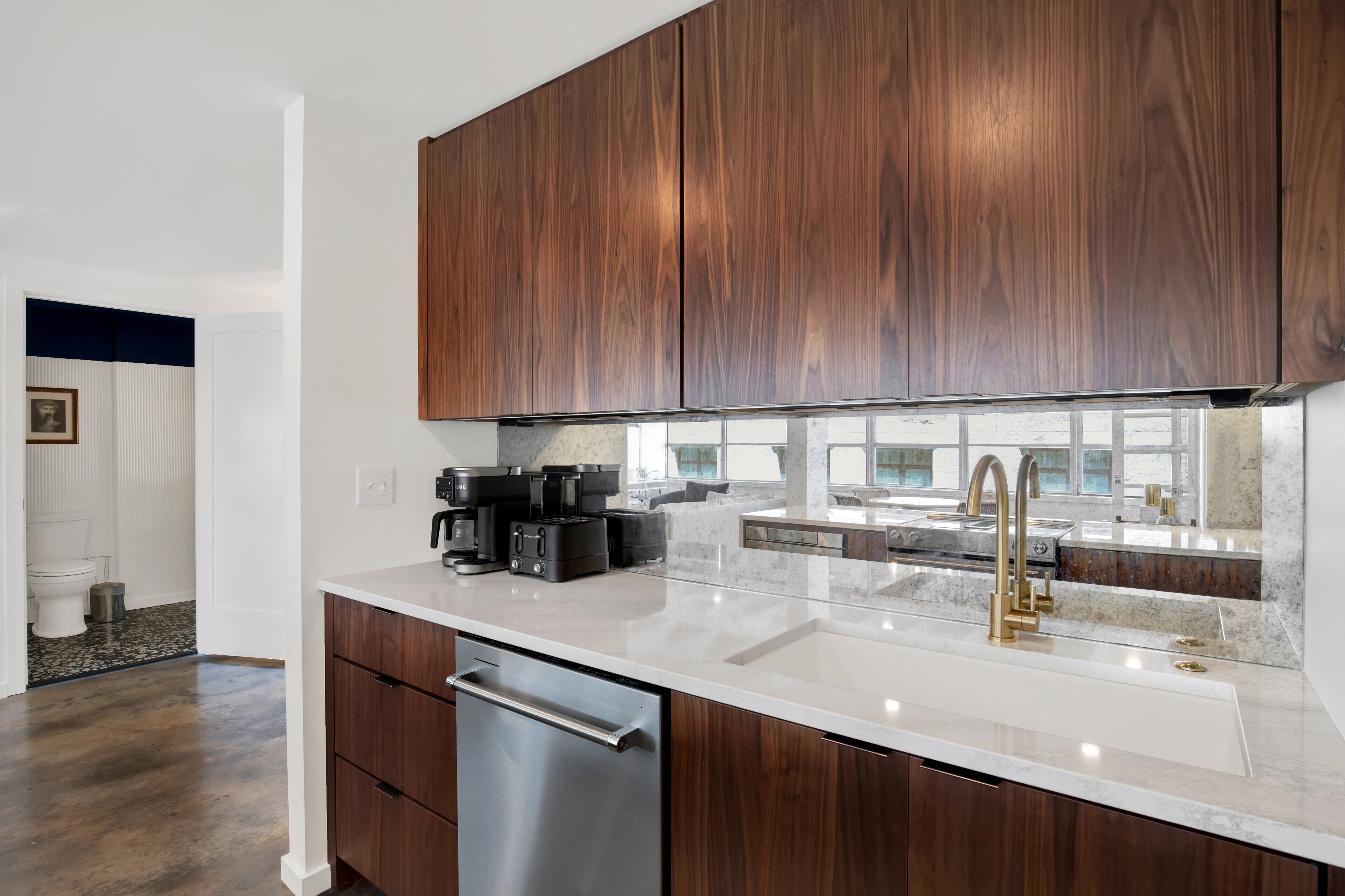 A modern kitchen with dark wood cabinets, a stainless steel dishwasher, and a white countertop.