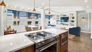 A modern kitchen with a large island, built-in appliances, and a dining area with a view. - Luxury Downtown Retreat | Heated Pool Access (Savannah)