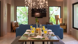 A dining area with a table set for four, featuring a bottle of champagne, glasses of orange juice, and a decorative centerpiece. - Villa in Hacienda Pinilla Near Beach – Private Pool, Golf Cart & Beach Club Access Included (Tamarindo)