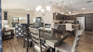A modern kitchen with dark cabinets, stainless steel appliances, and pendant lighting.
