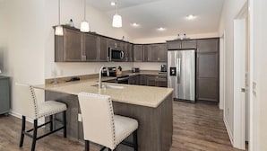 A modern kitchen with granite countertops, stainless steel appliances, and a central island with bar stools.