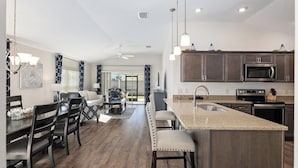 A modern kitchen with a central island, dark wooden cabinets, and stainless steel appliances.