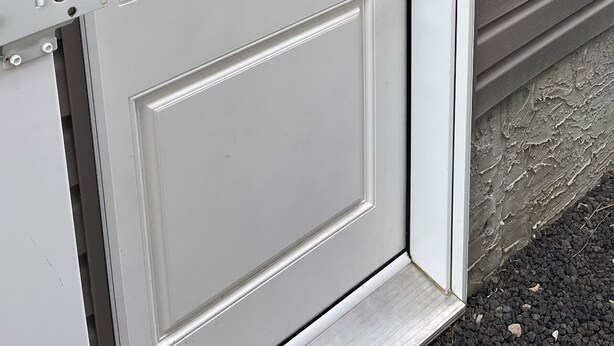 A white door with a black handle and a metal latch. - RaphaSuites (Regina)