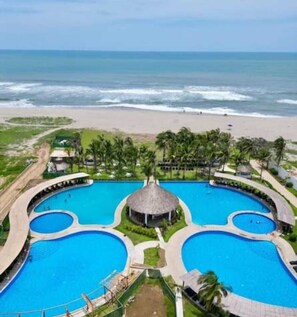 Un resort con varias piscinas, una playa y palmeras.