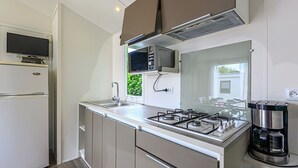 A compact kitchen with a built-in gas stove, a sink, and a refrigerator. - L'avocette by Interhome (Carnac)