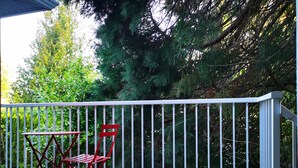 A balcony with a white railing, a red folding table, and a red folding chair. - Eagle's guest suits: two bedrooms living room private kitchen and full washroom (Victoria)