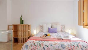 A bedroom with a bed, bedside tables, a wooden wardrobe, and a glass partition. - Stylish Duplex w/ Garage by HostWise (Porto)