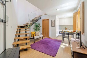 Um interior moderno com escada de madeira, área de refeições e cozinha.