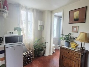 Compact kitchen area with a refrigerator, microwave, and potted plant.