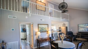 A spacious living area with a dining table, chairs, a white fan, and a kitchen in the background. - 3-bedroom house in fantastic family-friendly Surf City, 2 min walk to the beach. (Surf City)