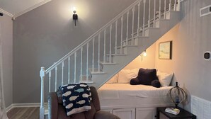 A bedroom with a bed, a chair, a small table, a globe, and a staircase. - 3-bedroom house in fantastic family-friendly Surf City, 2 min walk to the beach. (Surf City)