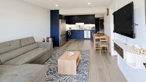 Ein modernes Wohnzimmer mit einer Couch, einem Couchtisch und einem an der Wand befestigten Fernseher.