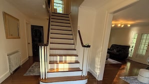 Un escalier en bois avec des rampes blanches menant à un deuxième étage.