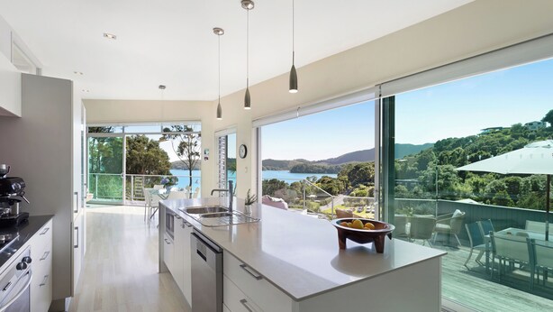 Una cocina moderna con una isla grande, vistas al exterior y un comedor con mesa y sillas.