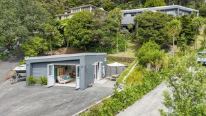 Una casa moderna con garaje, patio y vistas del bosque circundante.
