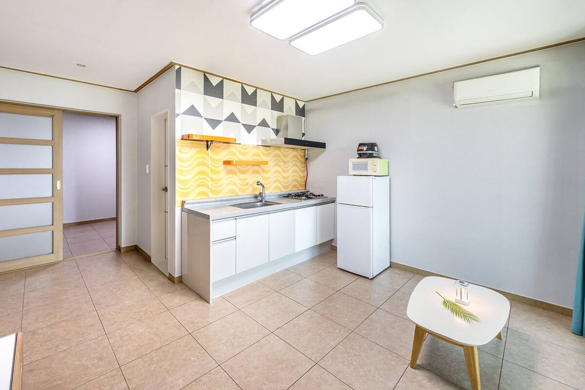 A compact kitchen with a gas stove, microwave, and a small dining area with a table and chair.