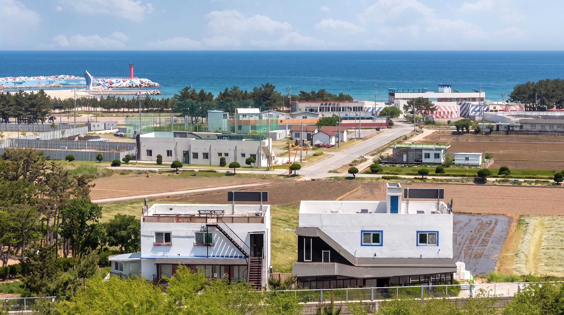 A coastal area with buildings, a lighthouse, and a beach.