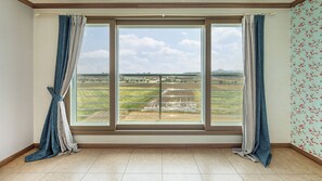 A room with a large window, curtains, tiled floor, and a floral wallpaper pattern. - Yeongdeok January and February Pension (Yeongdeok)