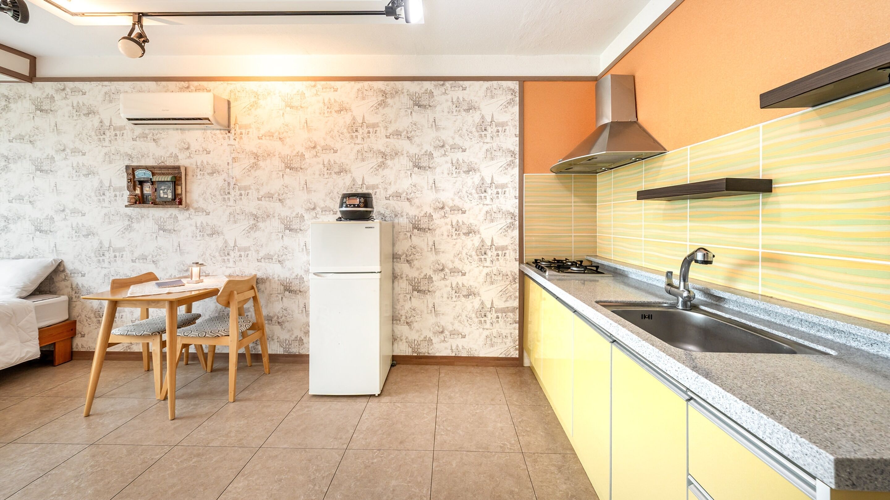 A compact kitchen with a refrigerator, stove, and sink. There is a dining area with a table and chairs.