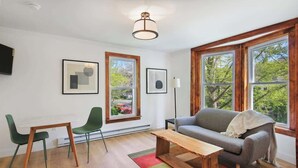 A modern living room with a sofa, two chairs, a coffee table, and large windows. - NY Suite | Downtown walk to Commons | Free Parking (Ithaca)