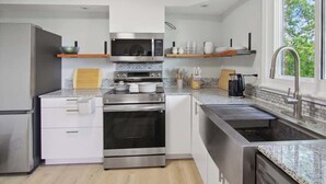 Una cocina moderna con electrodomésticos de acero inoxidable, armarios blancos y un ventanal que proporciona luz natural.