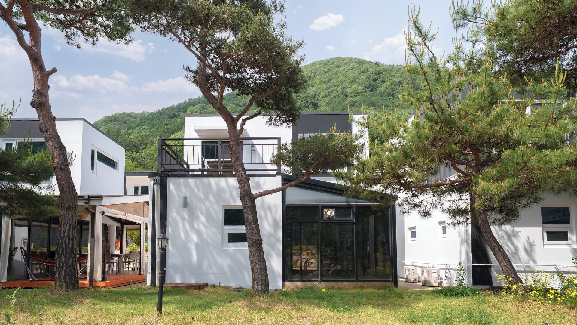 A modern building with a glass facade, surrounded by trees and a grassy area.