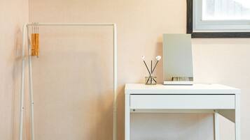 A minimalist bathroom with a white vanity, a mirror, and a small table with a bottle and two sticks.
