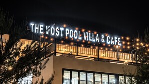 Un edificio con un letrero que dice "The Most Pool Villa & Cafe" de noche.