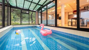 Una piscina interior con un flotador de flamenco rosa y una pelota de playa.
