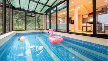 Una piscina interior con un flotador de flamenco rosa y una pelota de playa.