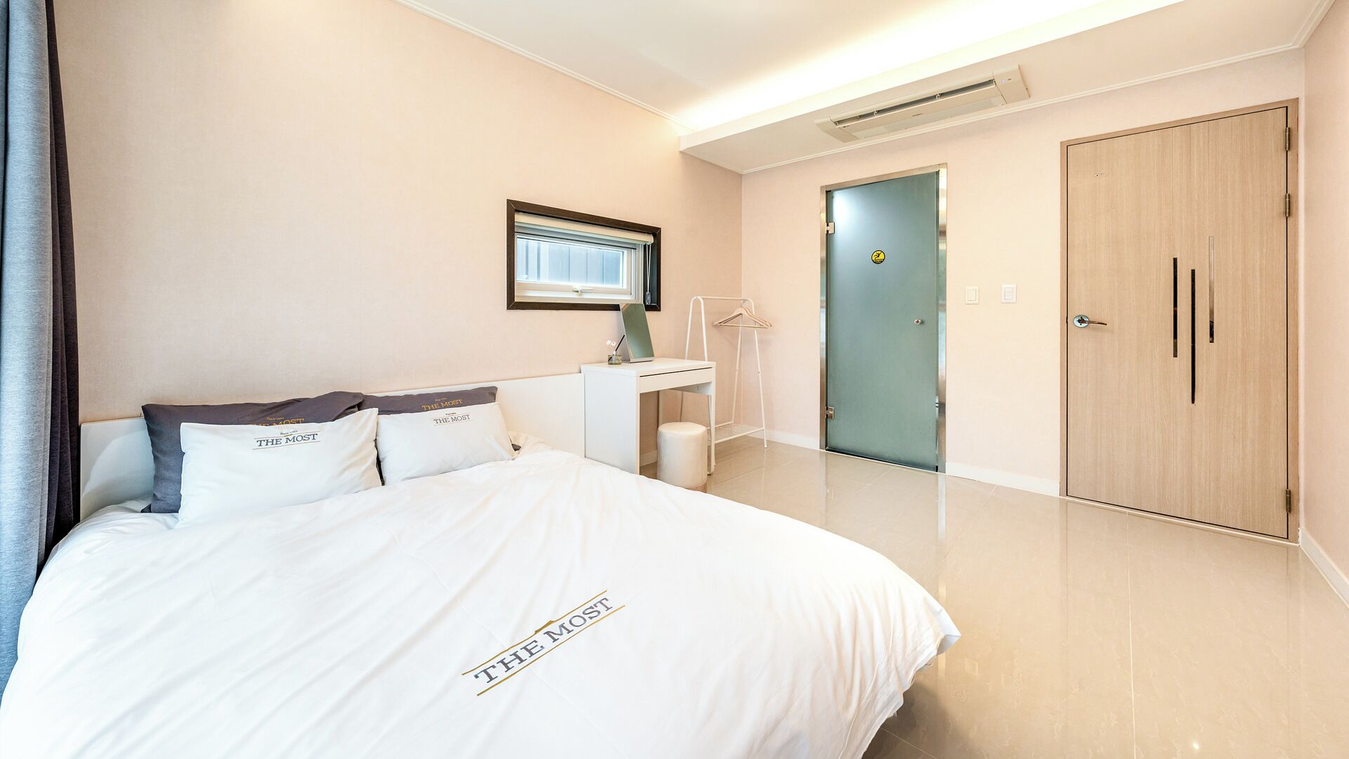 Una habitación de hotel con cama, escritorio, armario y puerta.