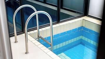 Una piscina con escaleras metálicas y paredes de azulejos.