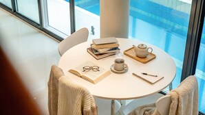 Una mesa redonda con libros, una tetera, una taza, vasos y un cuaderno.