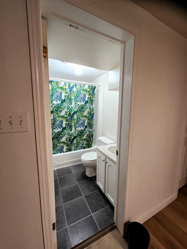 A bathroom with a shower curtain featuring a tropical leaf pattern, a toilet, and a sink.