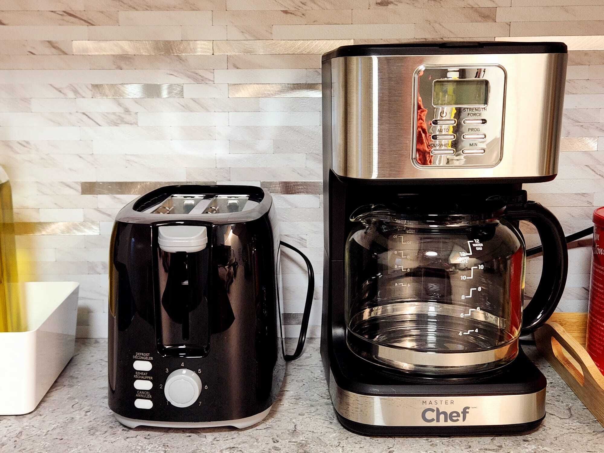 A kitchen with a black toaster and a stainless steel coffee maker with a digital display.