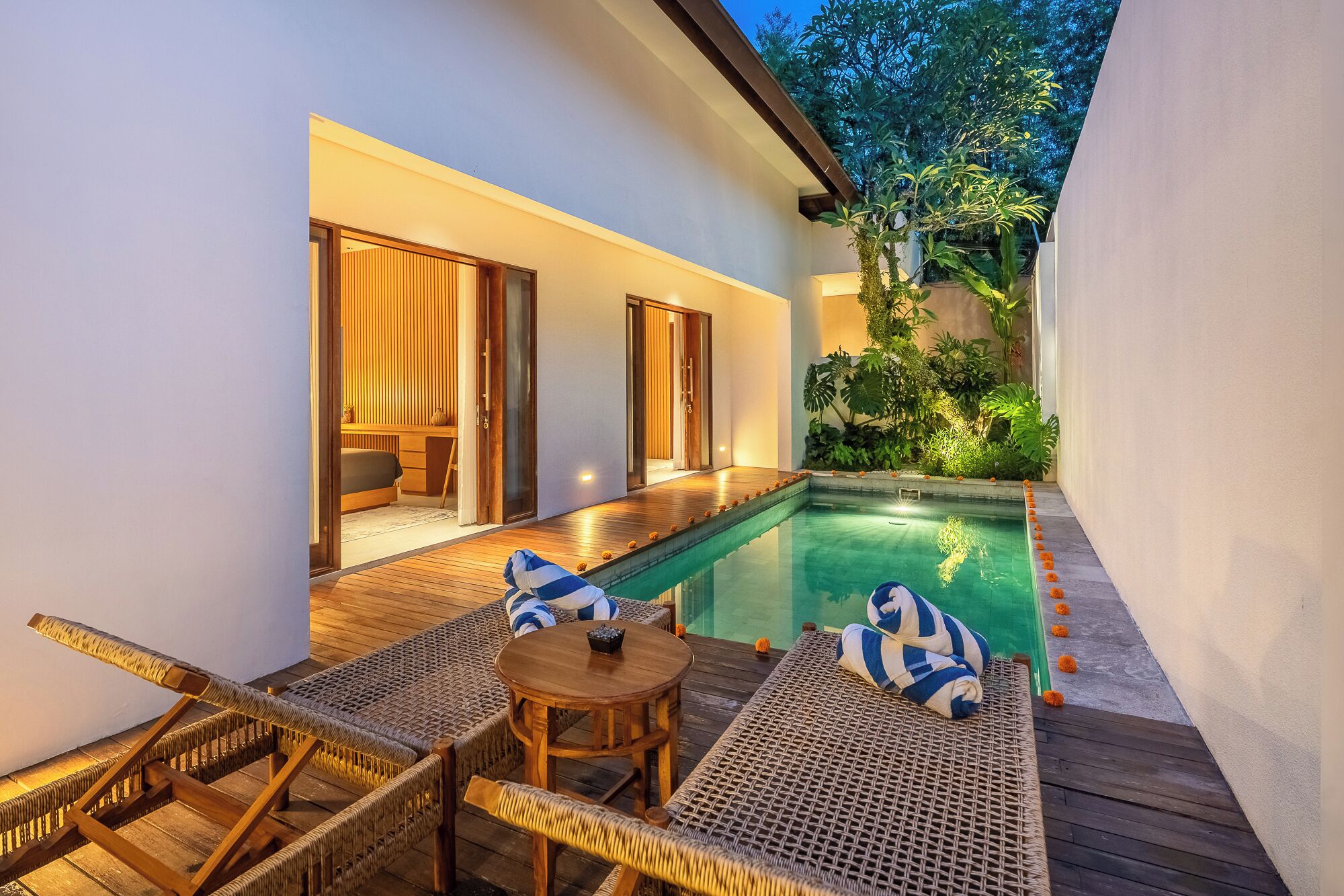 A private pool area with wicker furniture and a wooden deck.