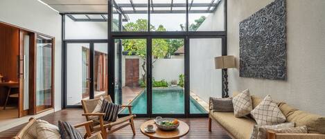 Un interior moderno con piscina, muebles de mimbre y una gran obra de arte abstracta.
