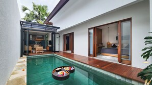 A modern pool area with a floating bar, a dining setup, and a bedroom with a large window. - Silk Umalas by Nagisa Bali (Kerobokan)