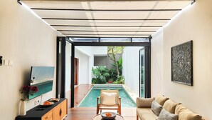 A modern interior with a wooden floor, a pool, a sofa, and a dining area. - Silk Umalas by Nagisa Bali (Kerobokan)
