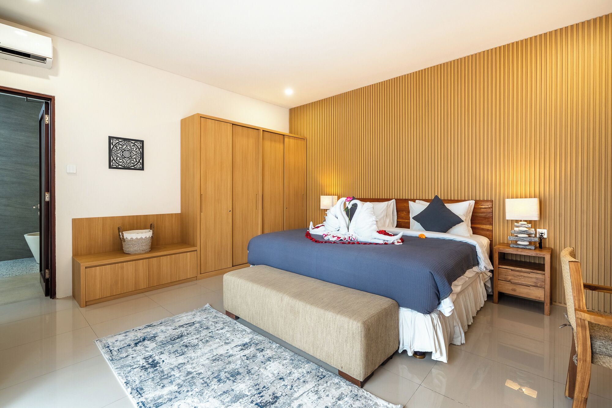A modern bedroom with a bed, a bench, a bedside table, and a wardrobe.