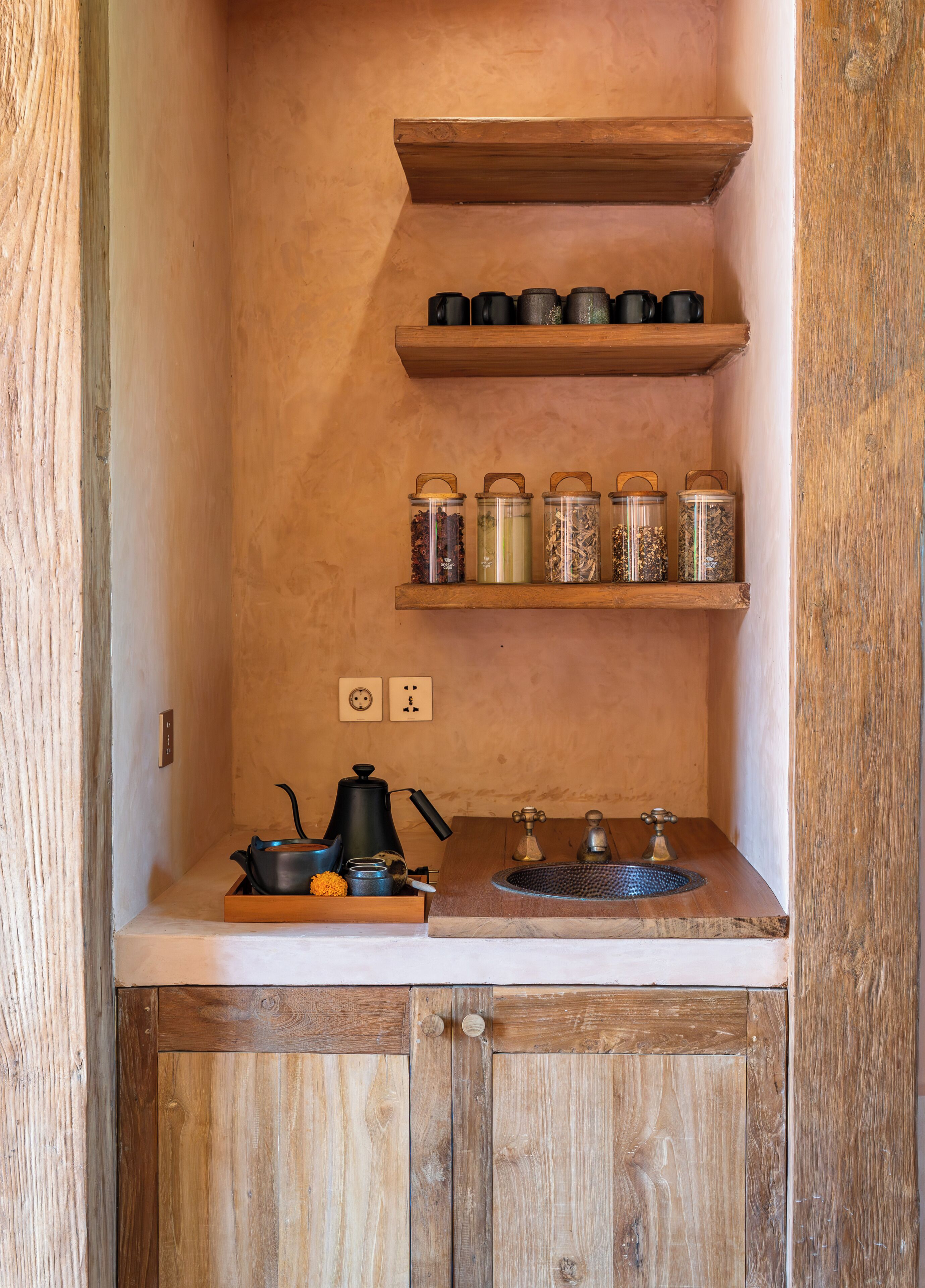 A compact kitchen with wooden shelves, a sink, and a coffee maker.