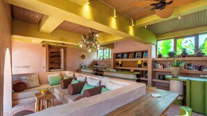 Un amplio salón con un sofá grande, una mesa de centro de madera y un ventilador de techo.