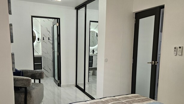 A bedroom with a bed, a sofa, a mirror, and a door. - Kick back and relax in this calm, stylish space. (Ponce)