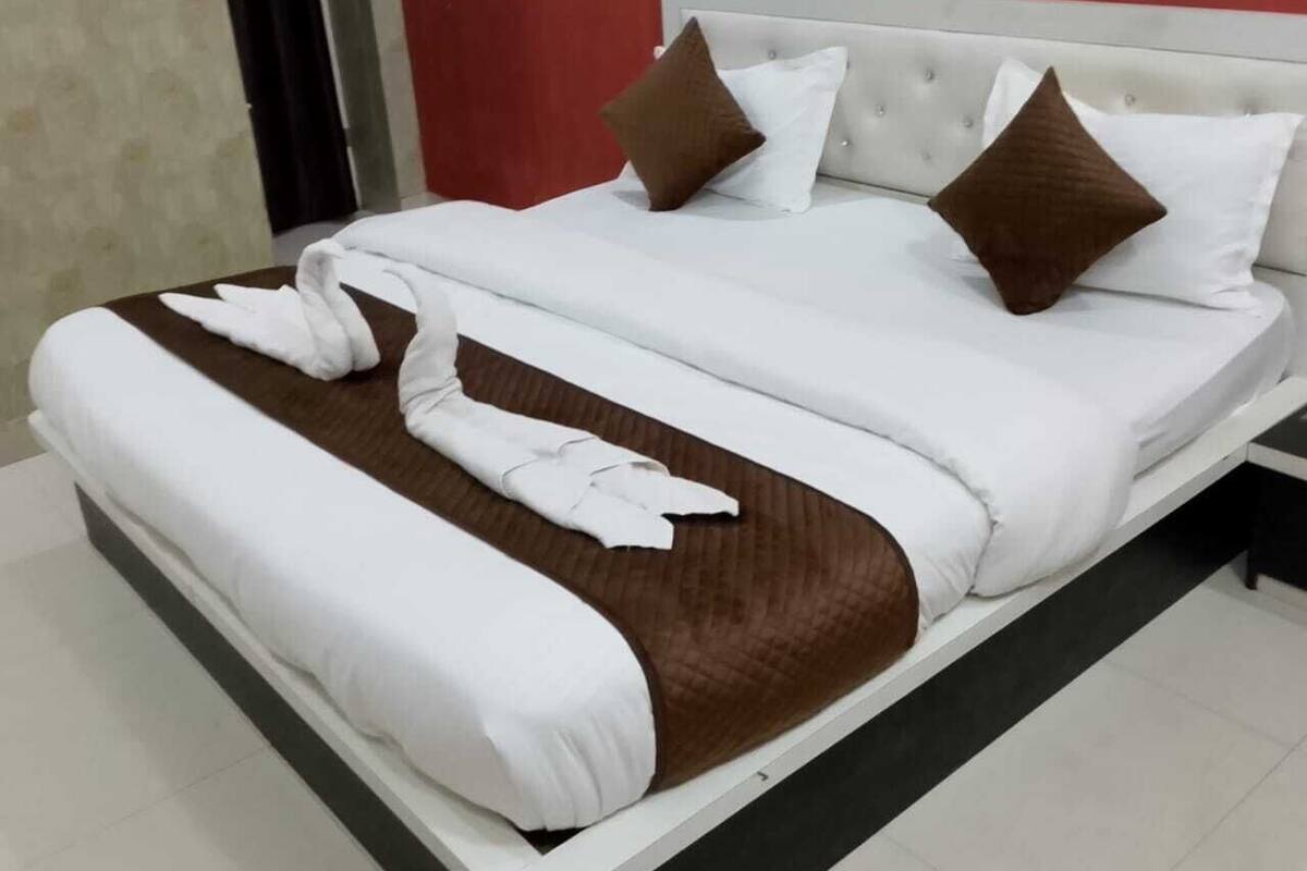 A neatly made bed with white and brown bedding, a tufted headboard, and a brown accent pillow.