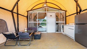 A tented accommodation with a dining area, chairs, a table, a refrigerator, and a view through the door. - Mungyeong The Most Glamping (Mungyeong)