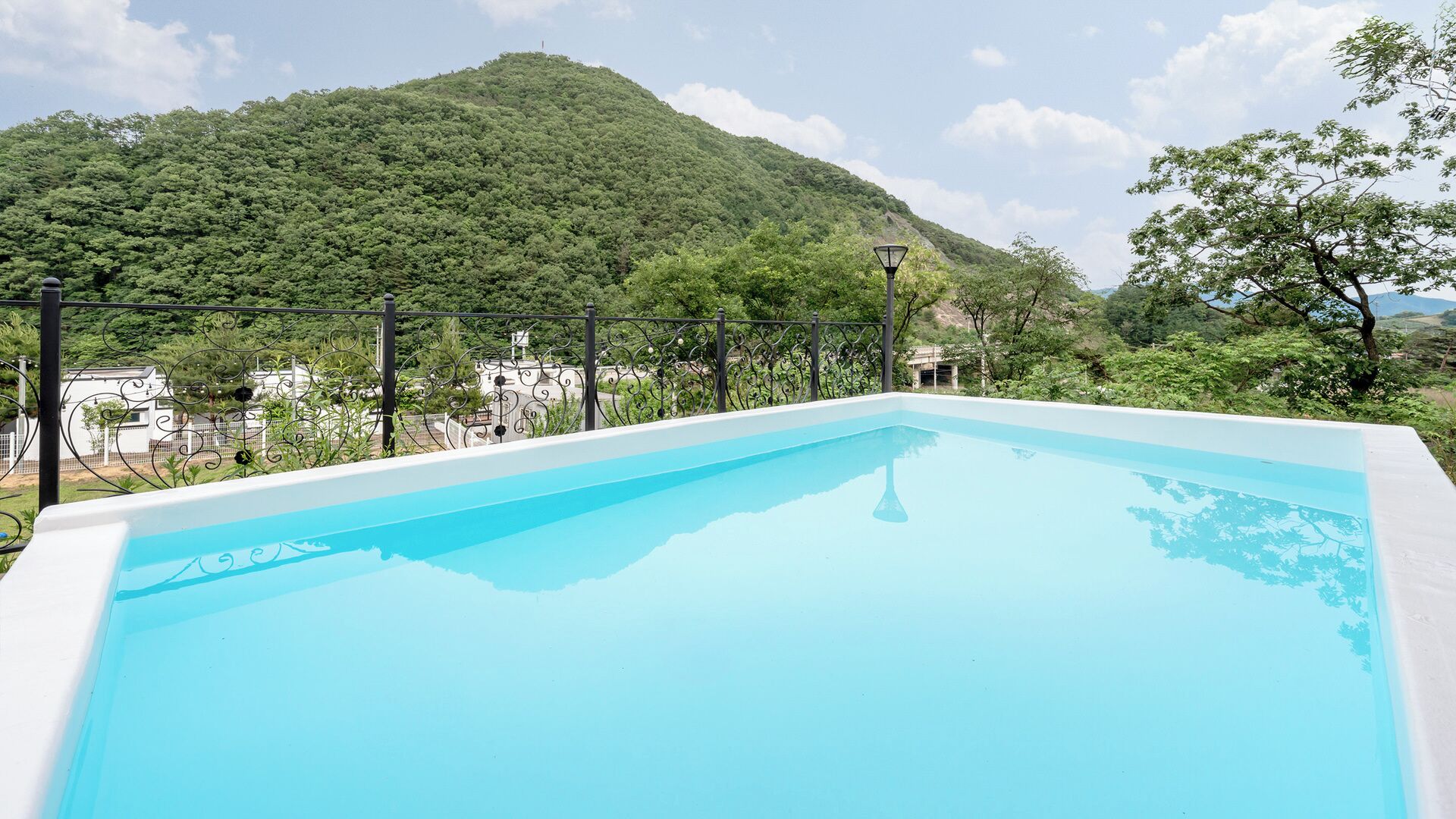 Una piscina con vistas a una montaña y un edificio blanco al fondo.